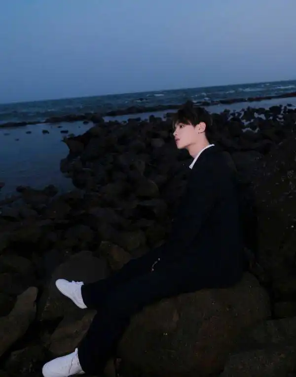 黄明昊海边氛围感写真,穿黑衣服与礁石融为一体,帅气俊逸彰显少年魅力
