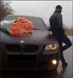 谁有一个外国男人靠着一辆车在等人车上放了一大束玫瑰花的原图
