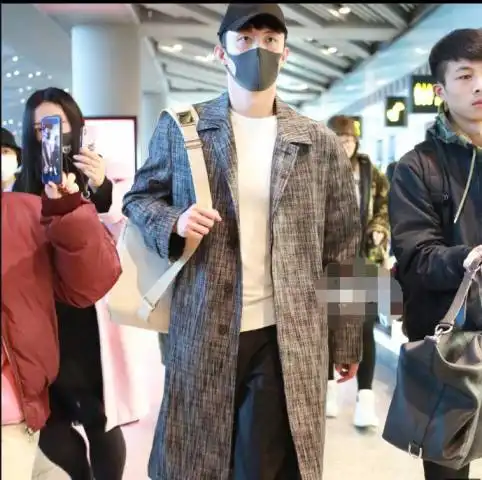 30亿票房男主黄景瑜穿着暗纹长款大衣戴着鸭舌帽现身机场帅气十足
